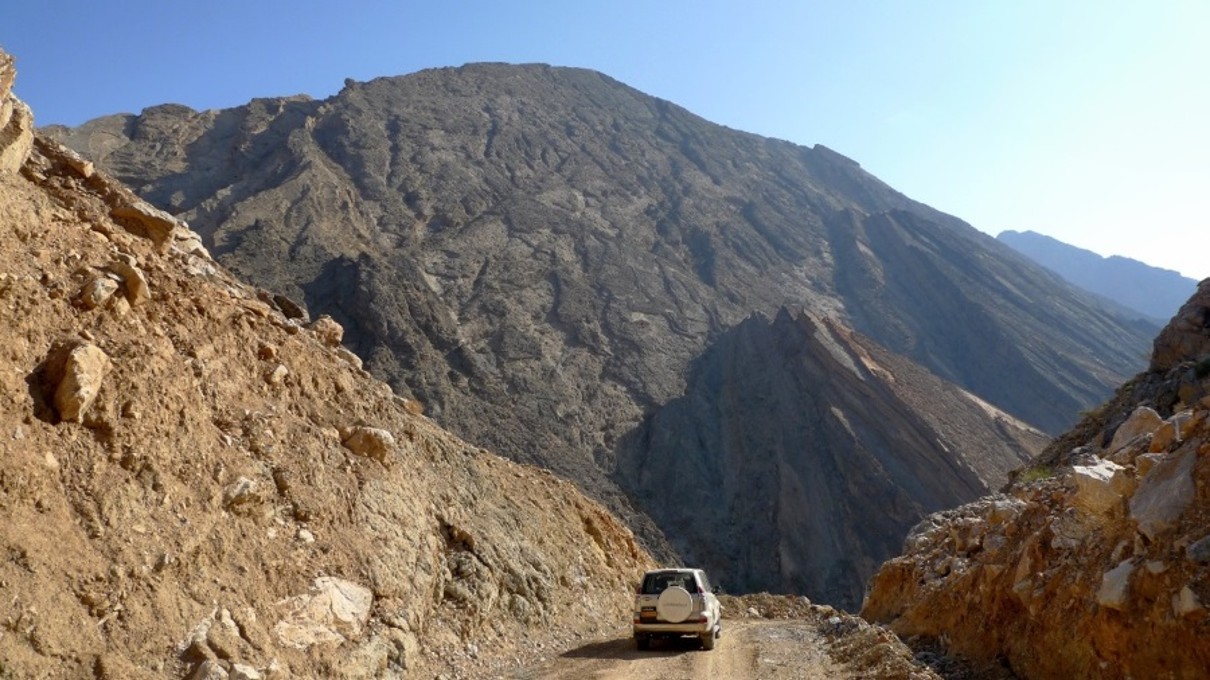 Allradfahrzeug umgeben von Bergen im Hajar-Gebirge