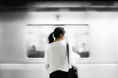 Asiatische Frau steht auf einem U-Bahn-Bahnsteig