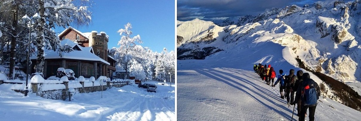 Snow-covered landscape with a house and trees on the left, snow-covered mountains and hikers on the right. 