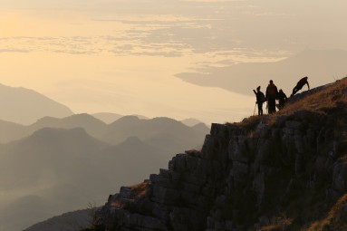 Four persons on top of a mountain, mountain panorama in the background. 